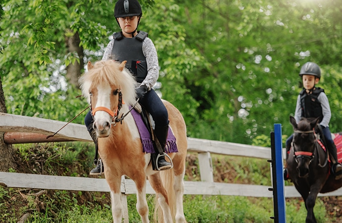 deux enfants cours équitation sur poneys