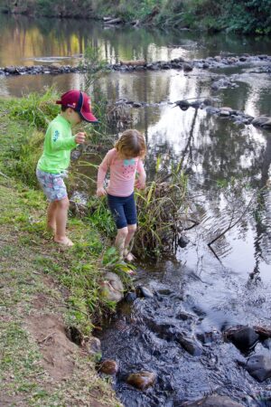 enfant les pieds dans une rivière découvre la nature