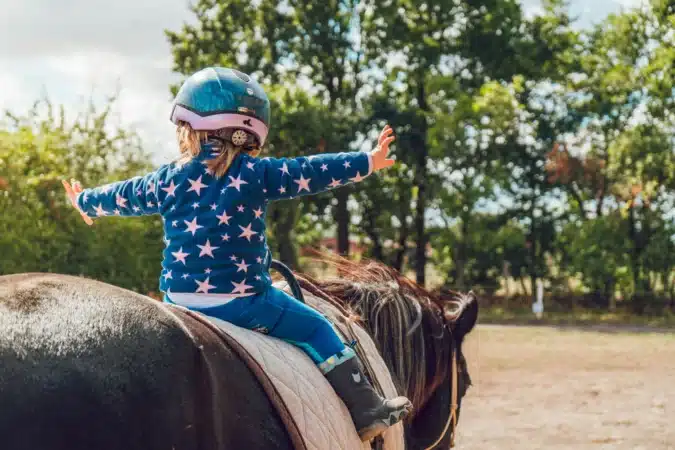 fillette sur un cheval en cours d'équitation