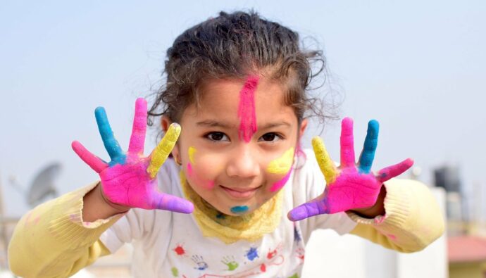 élève en atelier peinture mains et visage colorés